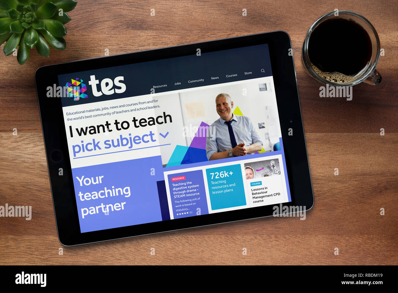 The website of Tes (formerly the Times Educational Supplement) is seen on an iPad tablet, resting on a wooden table (Editorial use only). Stock Photo