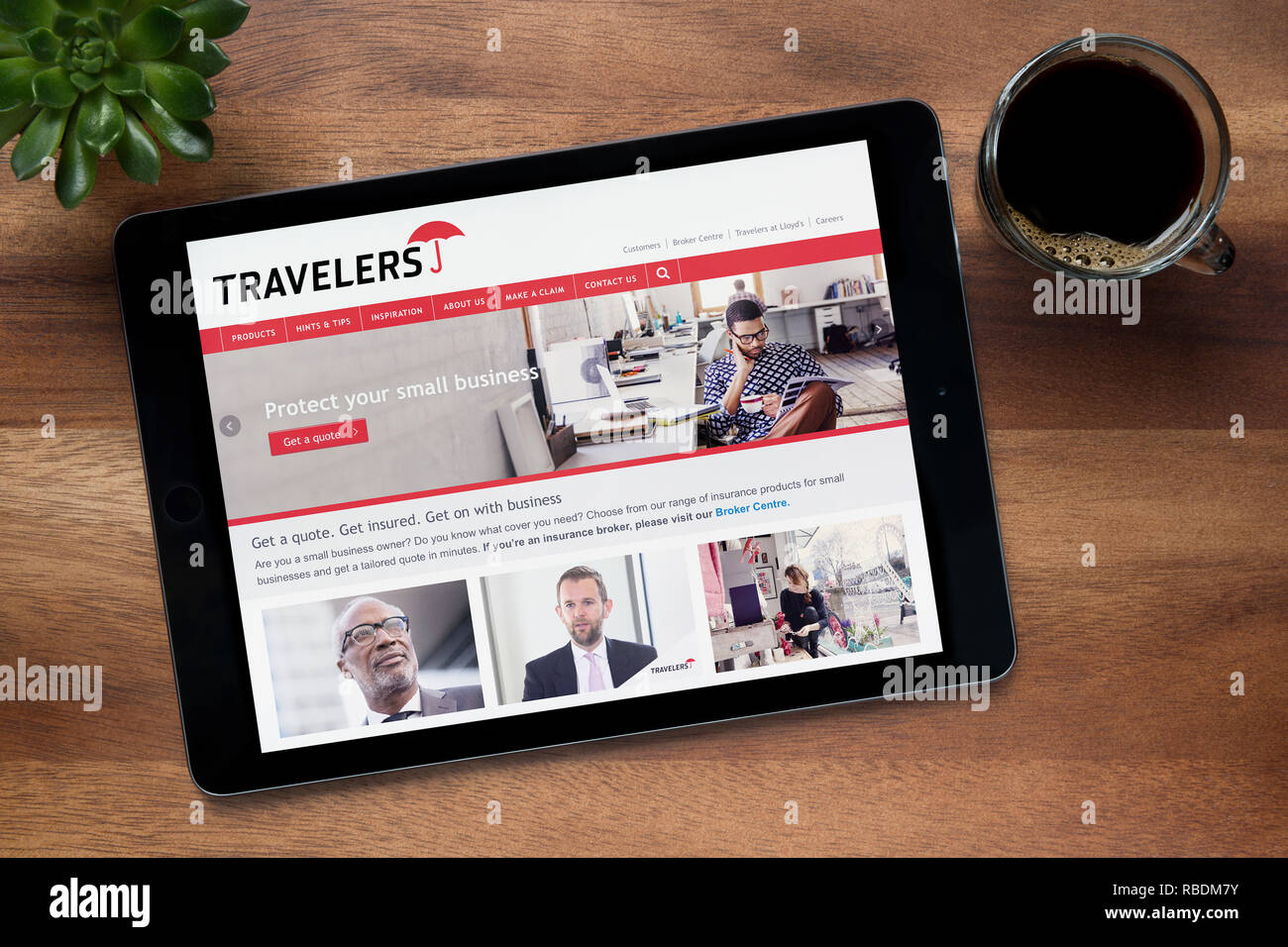 The website of Travelers business insurance is seen on an iPad tablet, resting on a wooden table (Editorial use only). Stock Photo