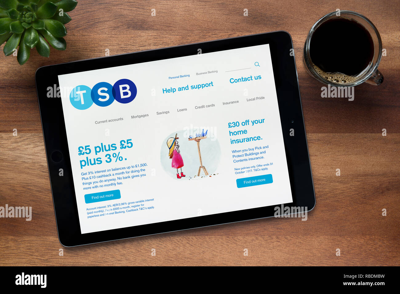 The website of TSB bank is seen on an iPad tablet, on a wooden table along with an espresso coffee and a house plant (Editorial use only). Stock Photo