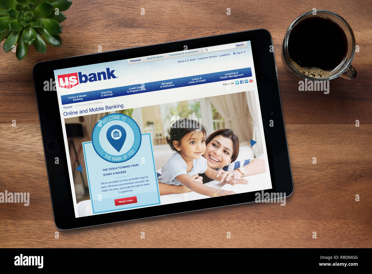 The website of US Bank is seen on an iPad tablet, on a wooden table along with an espresso coffee and a house plant (Editorial use only). Stock Photo
