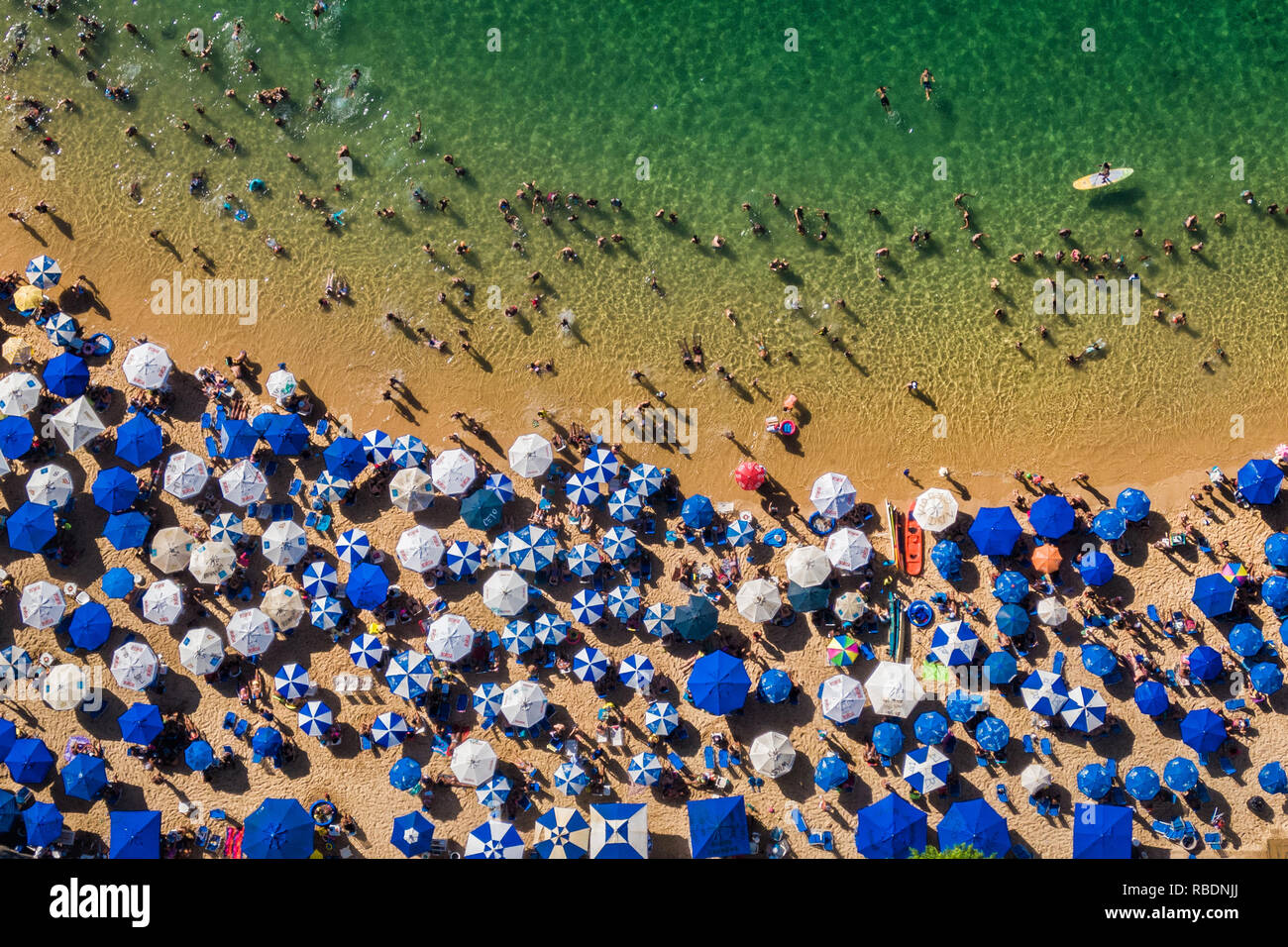 Salvador da Bahia, Brazil, aerial top view of umbrellas and people relaxing and bathing at Porto da Barra Beach in the summer. Stock Photo