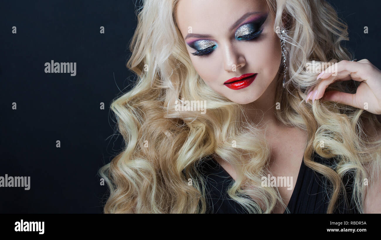 Portrait of a young luxurious blonde with long curls. bright makeup for ...