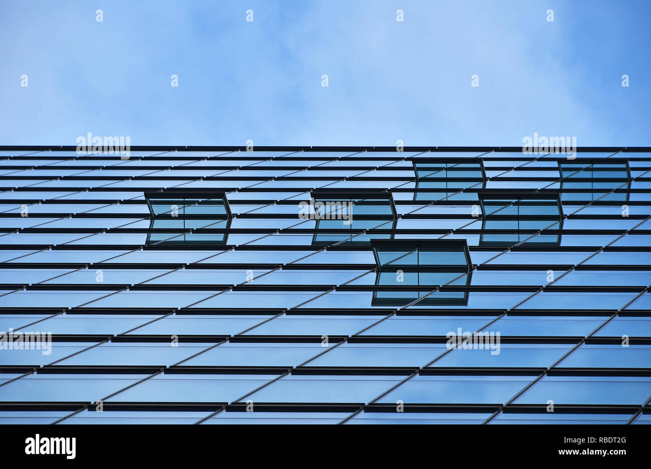 Background texture of modern business skyscraper building glass windows pattern with reflection over cloudy blue sky, low angle view Stock Photo