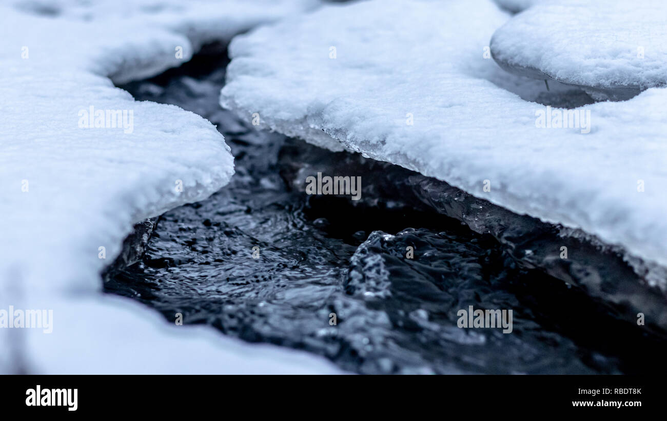 frozen river melting with a beautiful cold water running under the ice
