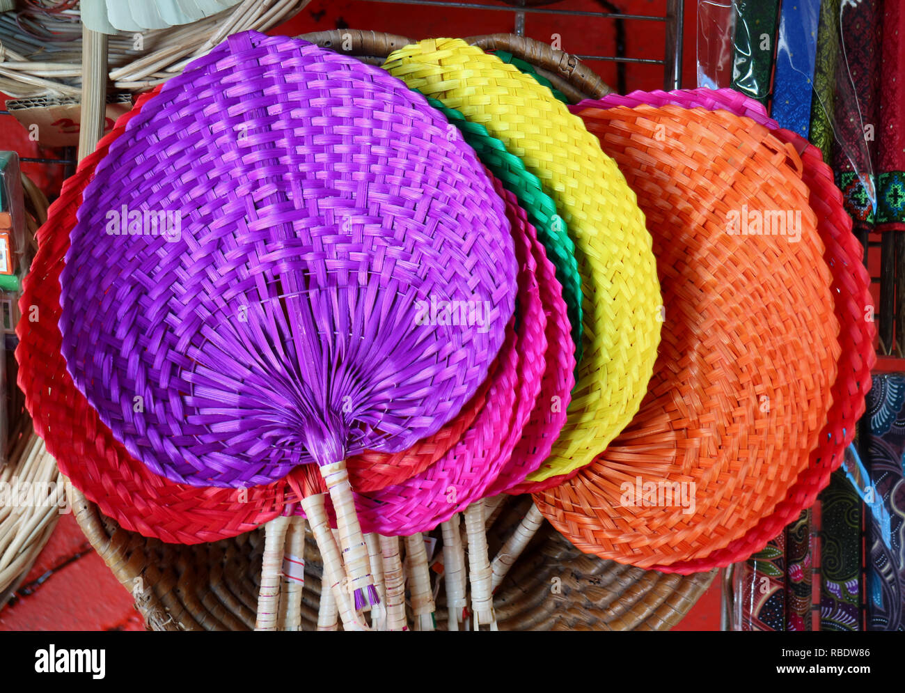 Colorful handmade natural raffia fans displayed in the shop at flea market in Thailand Stock Photo