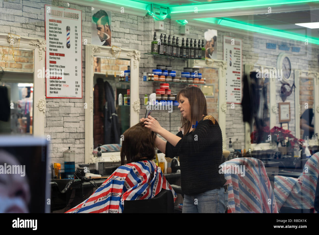 A Woman Hairdresser Cutting A Clients Hair With A Pair Of Scissors