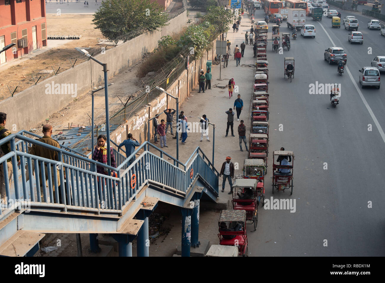 Traffic interchange outside Sarita Vihar Metro station in New Delhi: A row of rickshaws wait for metro passengers alongside the busy road. Stock Photo