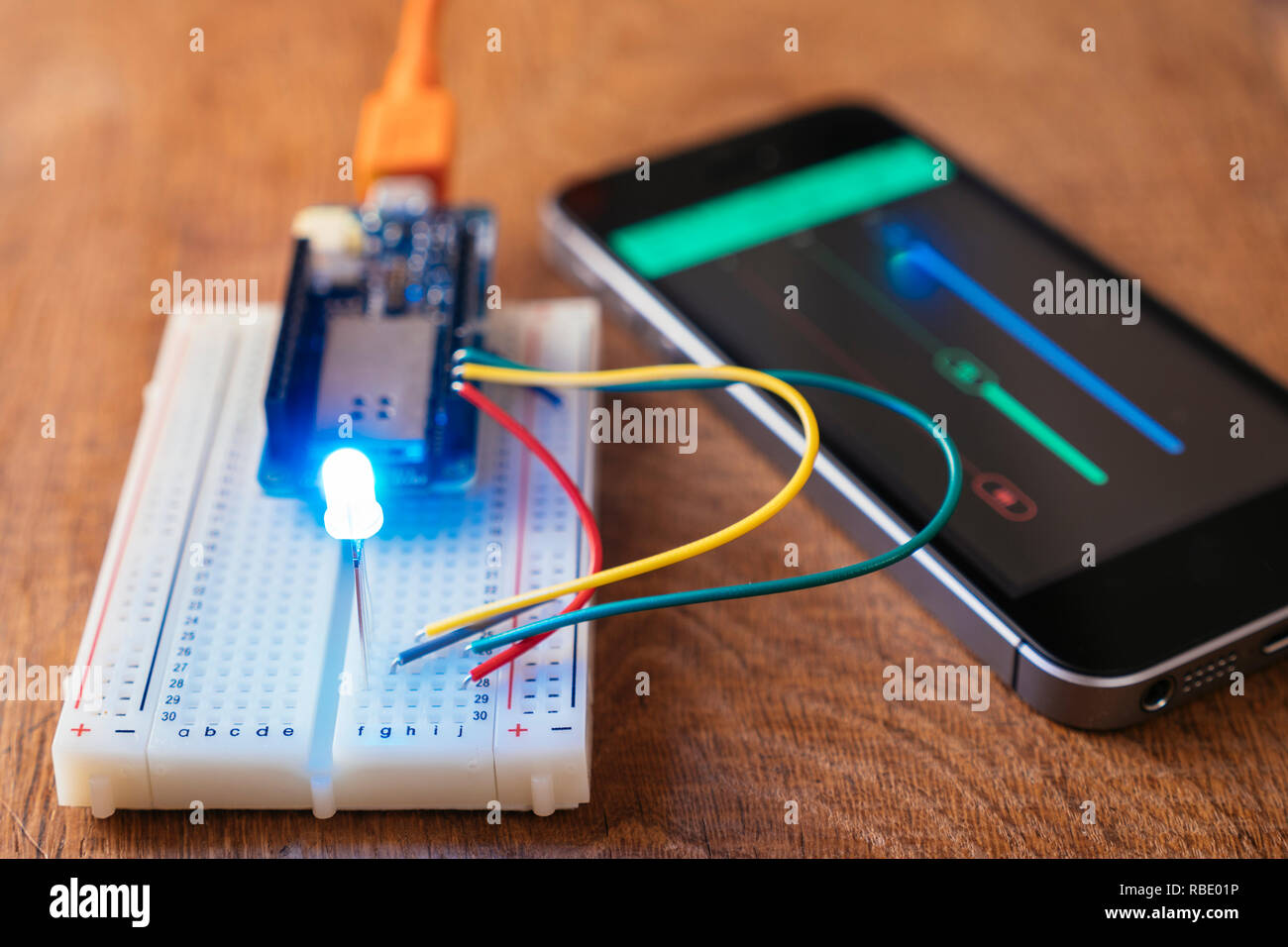 RGB Led on a breadboard with microcontroller board being controlled by a mobile phone app. Stock Photo