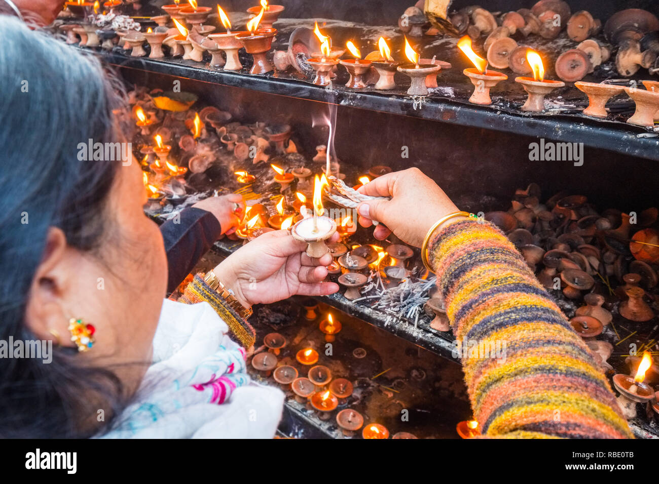 Nepalese woman lighting candles at a temple in Kathmandu,Nepal Stock