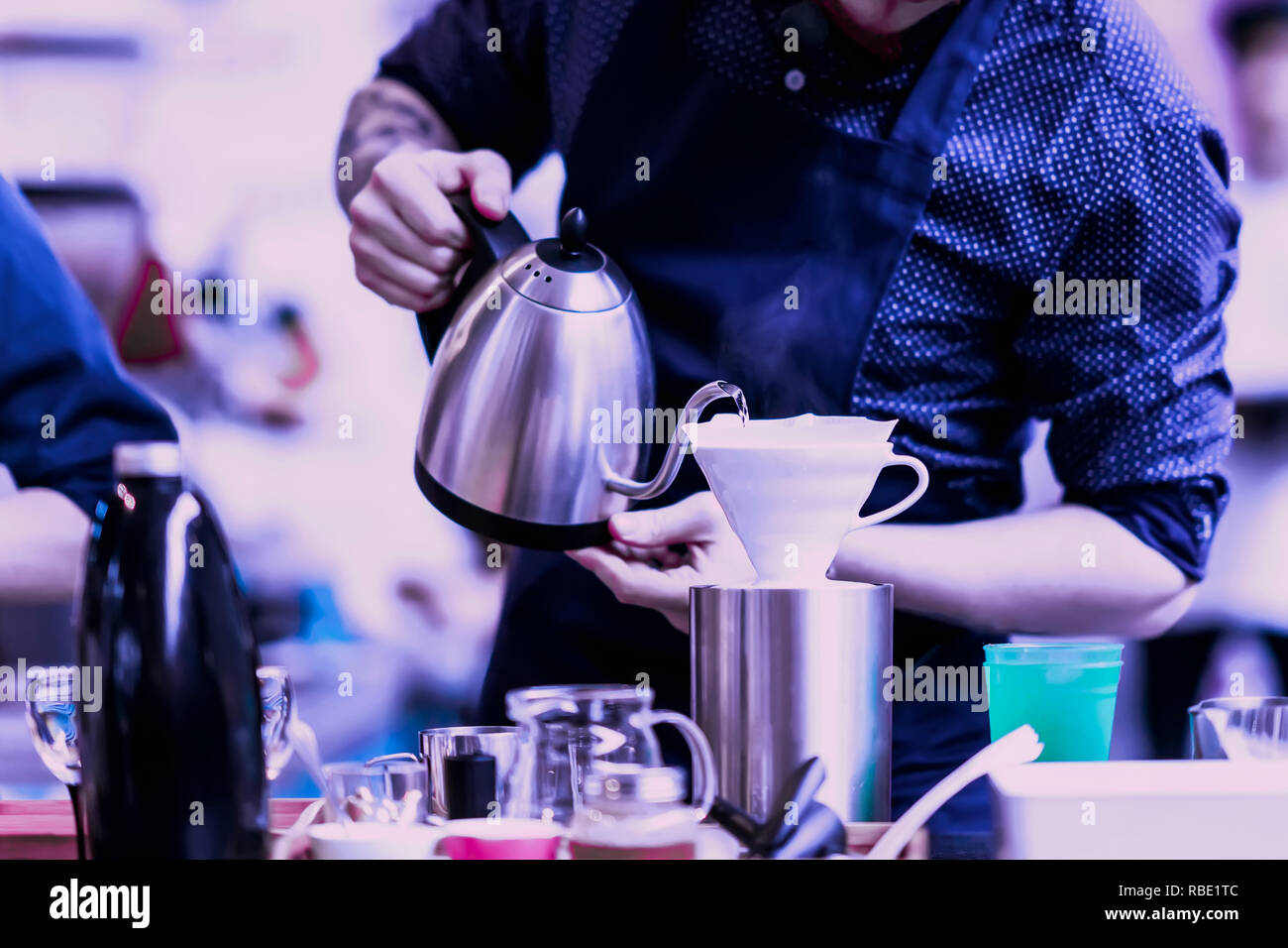 Professional barista pouring boiling water from special kettle into