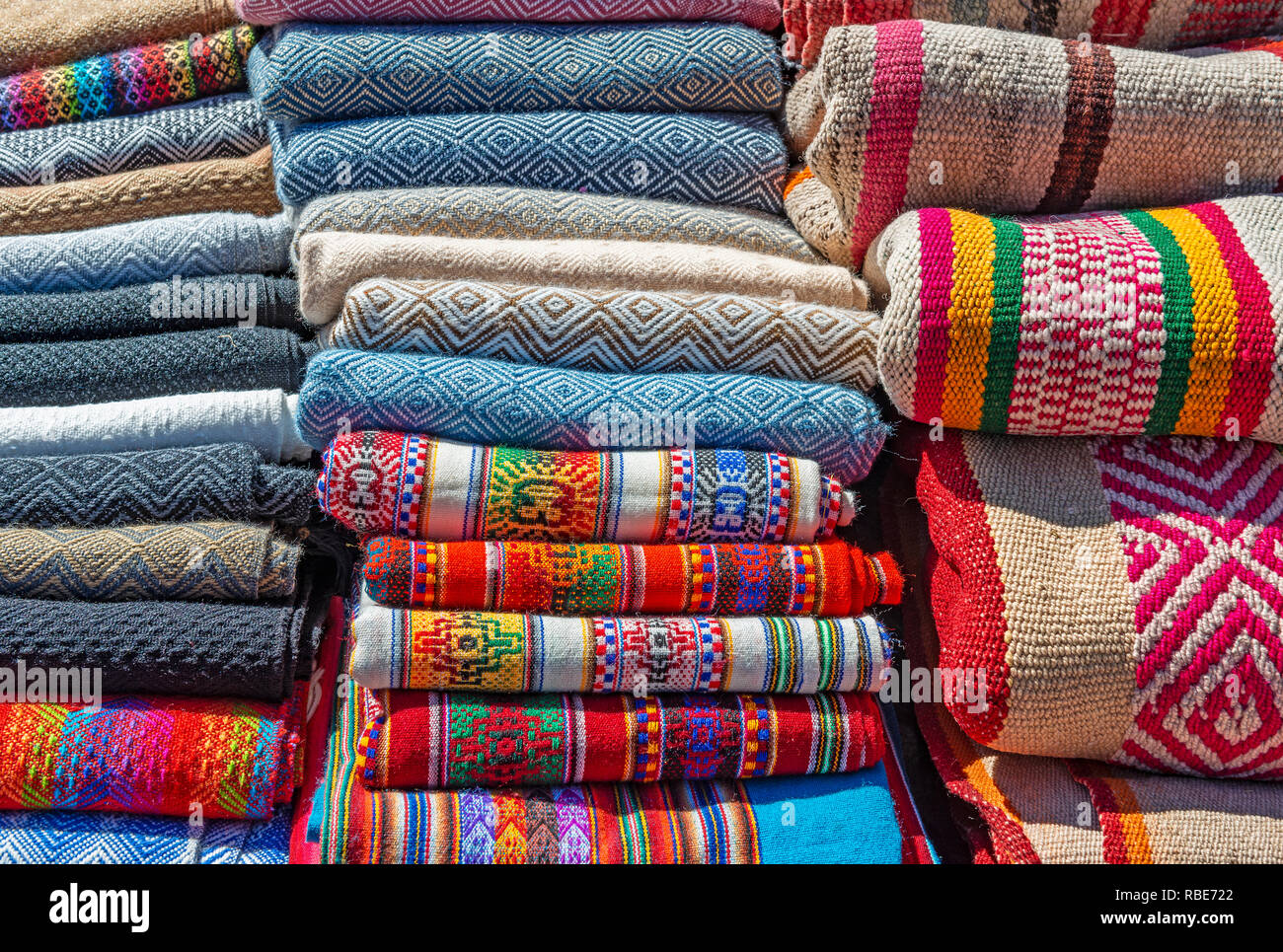 A pile of traditional alpaca wool Andes textiles on a market stall in the Sunday market of Pisa near Cusco, Peru. Stock Photo