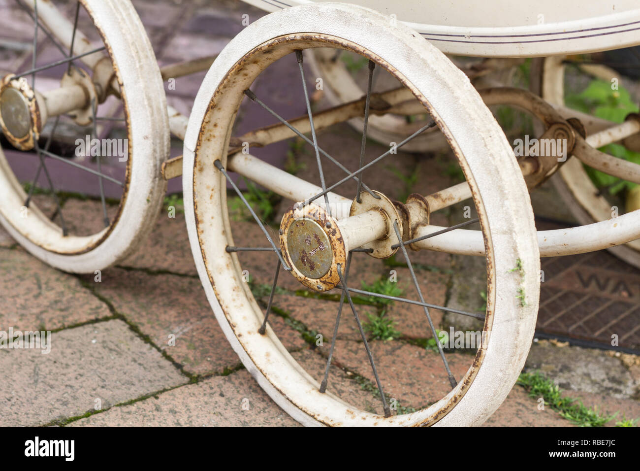 The rusted spokes and wheels of a vintage baby carriage on the street in Horsham, Mid Sussex Stock Photo