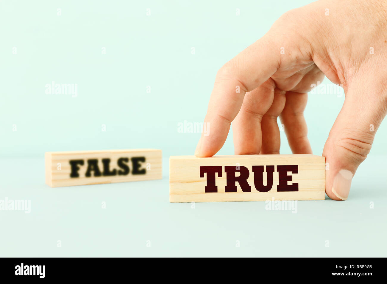 true or false concept man hand picking wooden cubes with text over wooden blue background Stock Photo