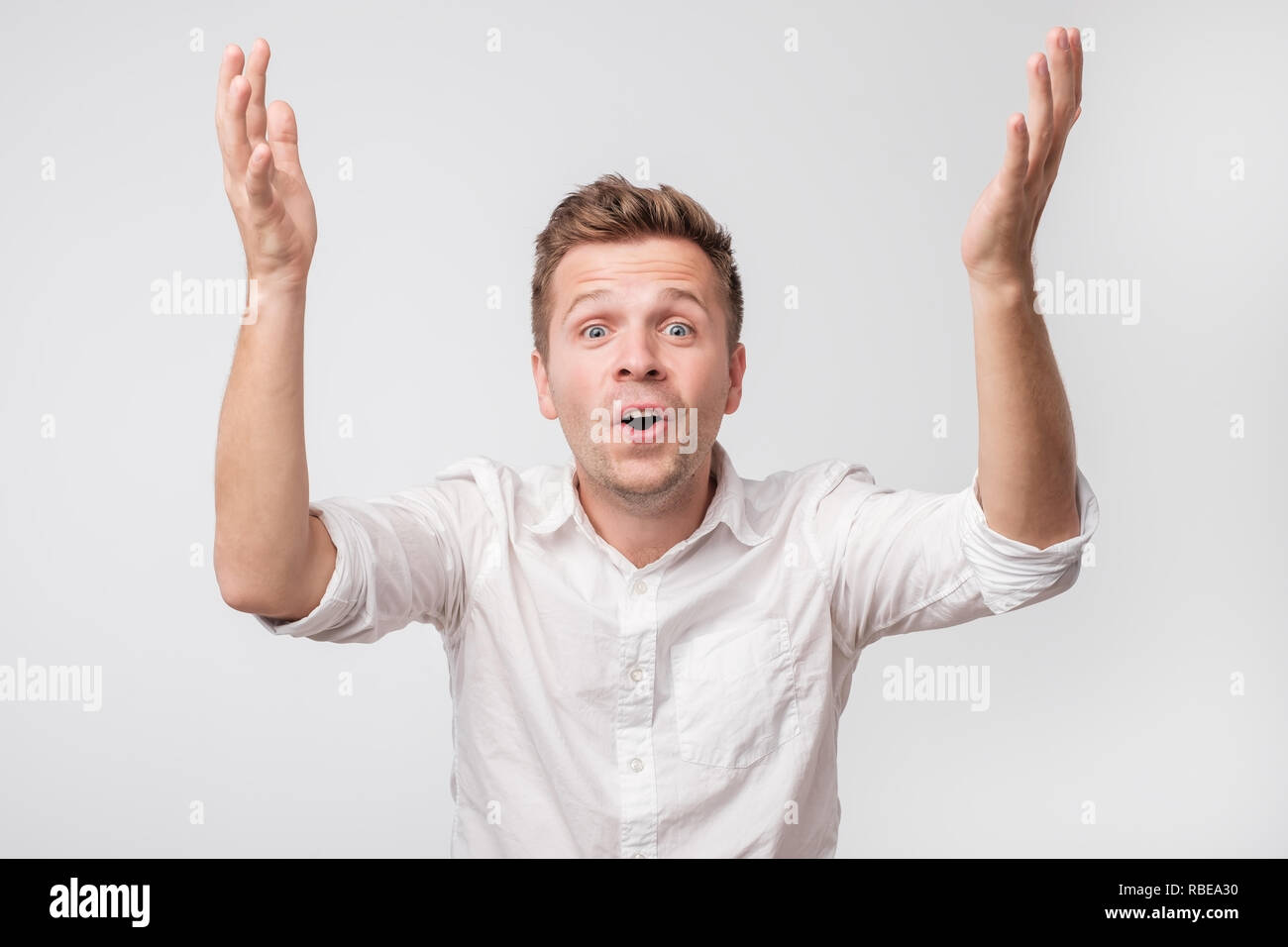 Glad man looks with surprise and amazement face, raising hands up. Stock Photo