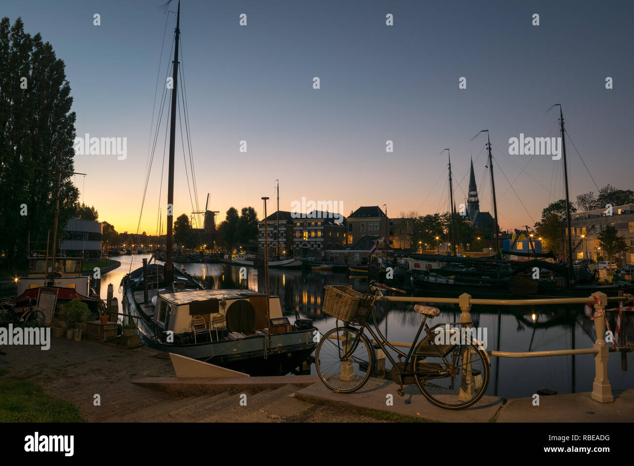Twilight colors over the old harbor of Gouda in Holland. Scenic, typical dutch view of several landmarks in the city of Gouda, The Netherlands. Stock Photo