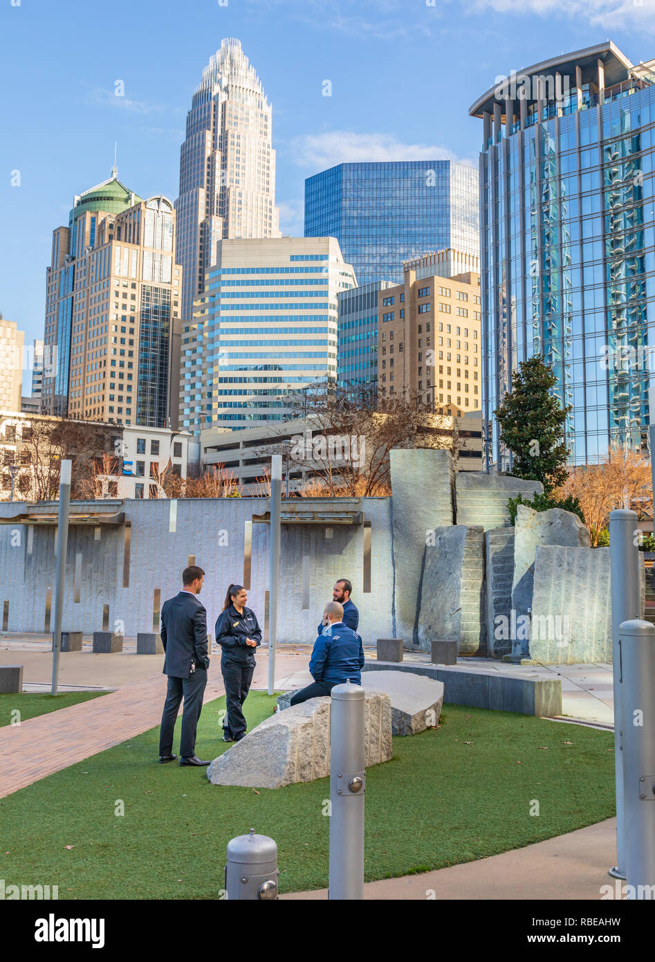CHARLOTTE, NC, USA-1/8/19:  Four people, 3 men and one woman, stand in grassy area of Bearden park and socialize. Stock Photo