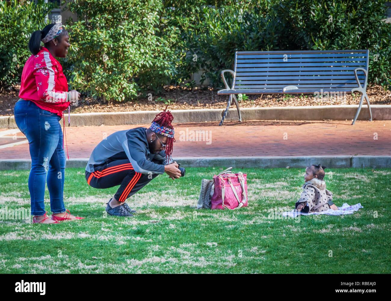 CHARLOTTE, NC, USA-1/8/19: A young black couple photographing infant in Romare Park in uptown.  Tight crop. Stock Photo