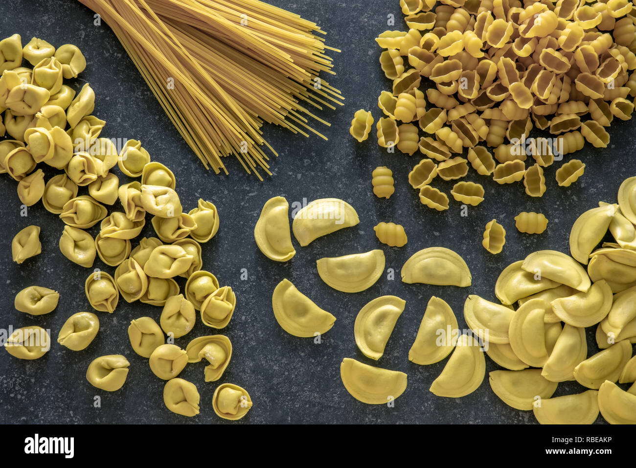 Various traditional italian pasta on dark stone background. Stock Photo