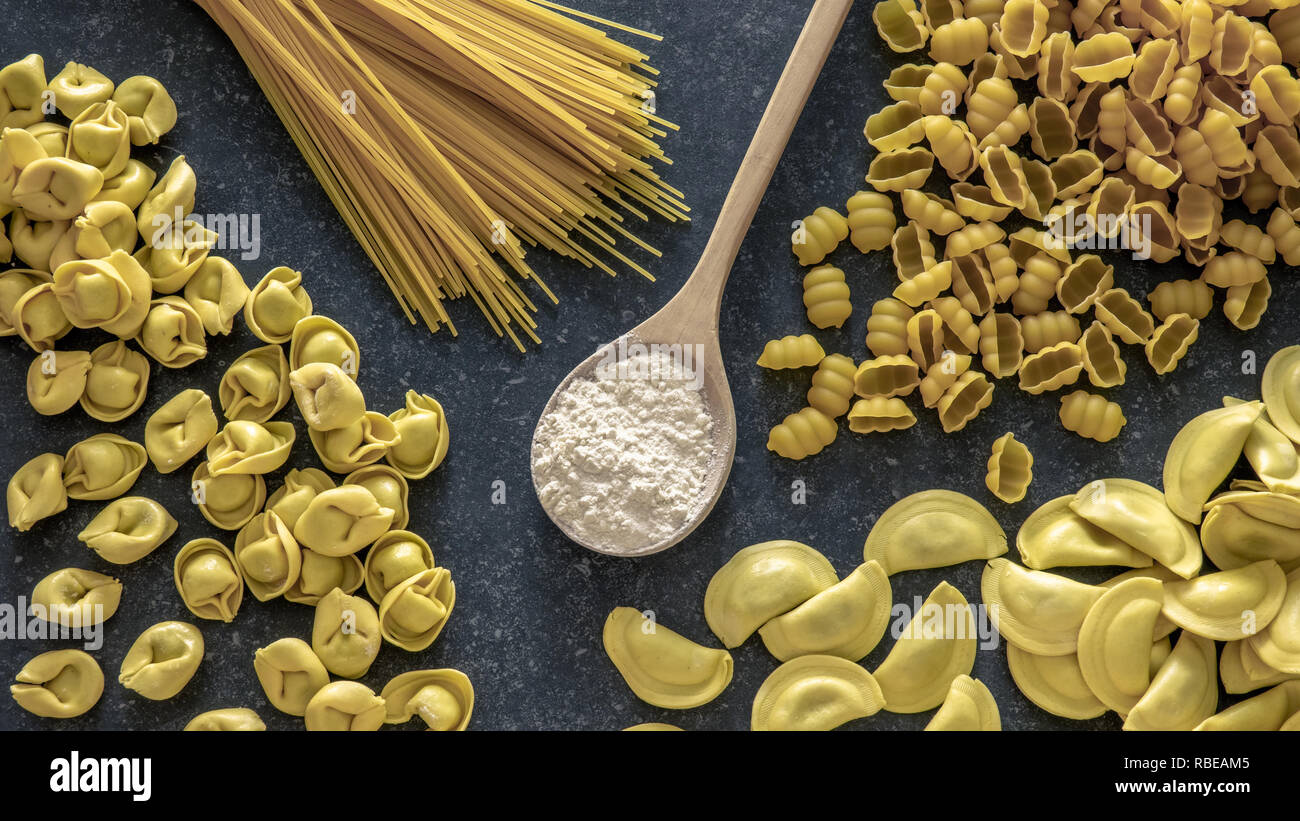 Various pasta and flour on dark stone background. Gluten free food concept. Stock Photo