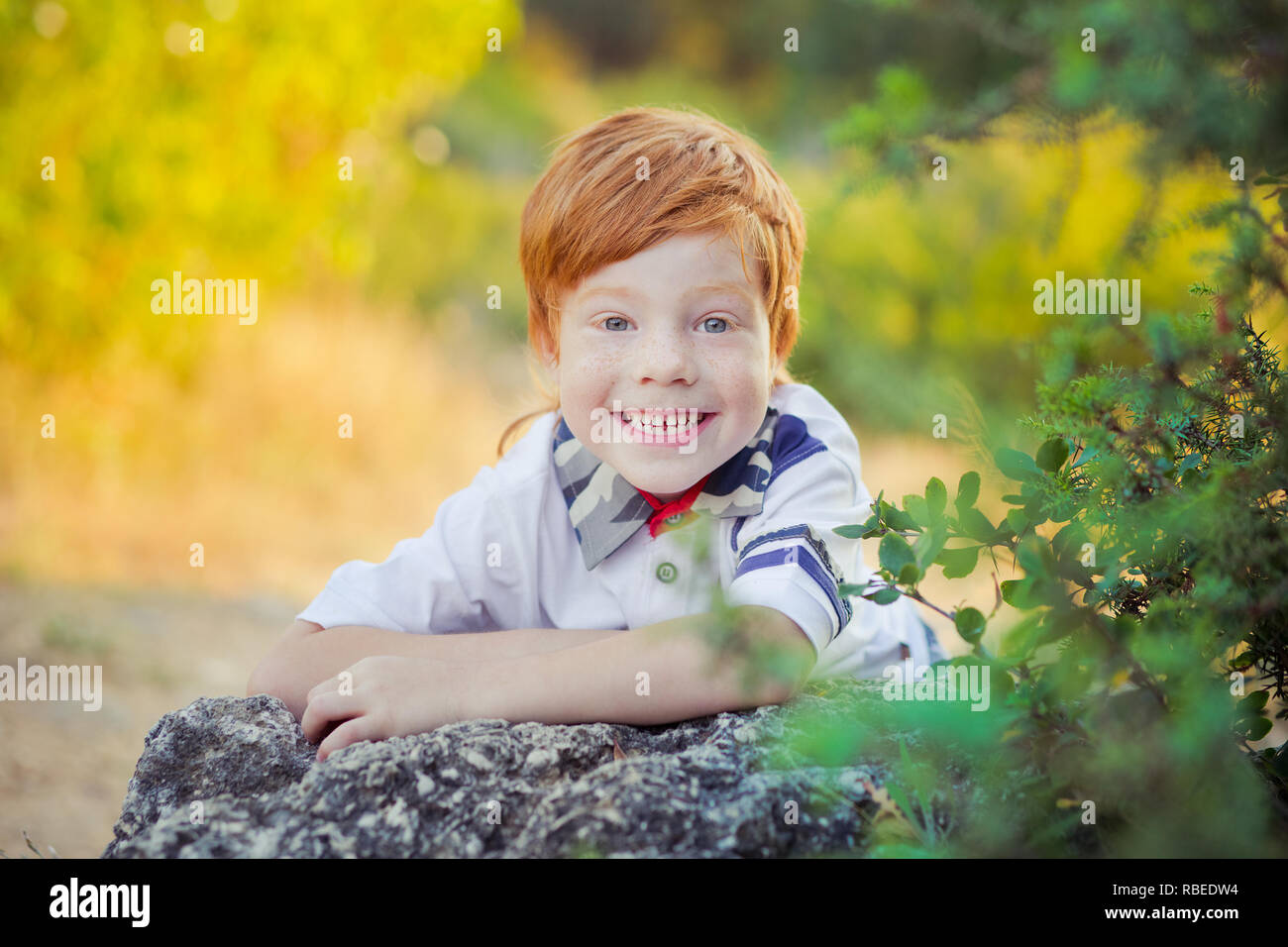 Cute red hair boy smiling to camera and standing in forest Stock Photo