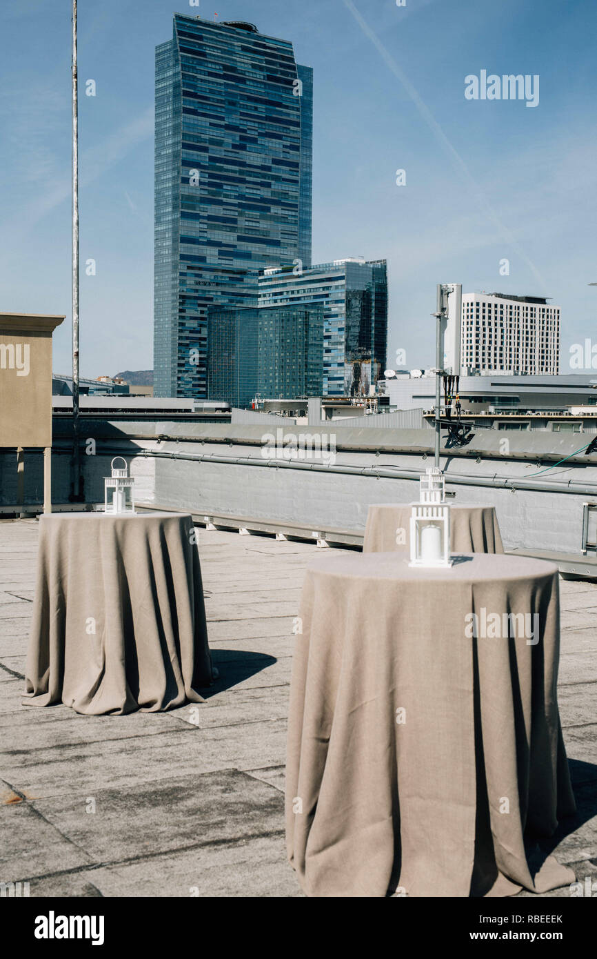 empty cocktail dinner tables on rooftop with large skyscraper Stock Photo