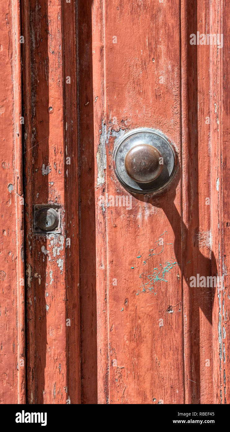 Photograph of a red, weathered wood door of a small village in Tuscany. Brass handle is worn and keyhole is covered with a spiderweb. Stock Photo
