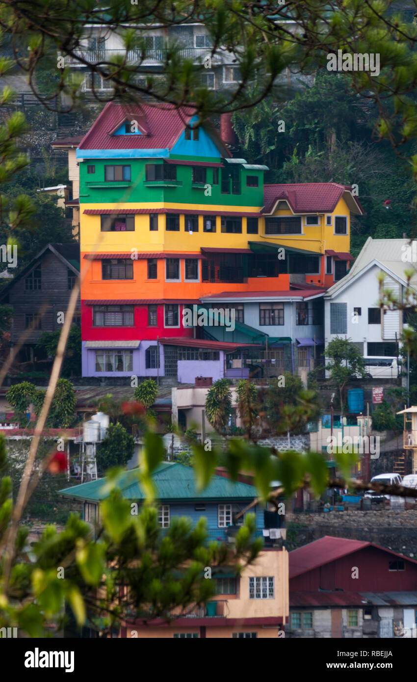 Tall house, brightly painted in many colours, stands out from the crowd in mountain city of Baguio, Philippines. Stock Photo