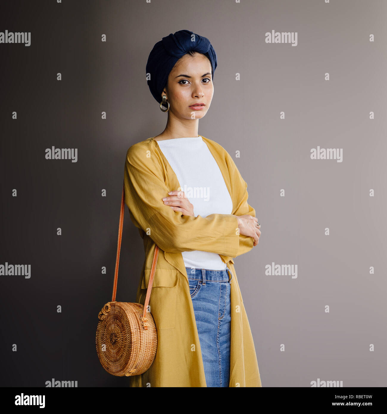 Studio portrait of a young, elegant and beautiful Middle Eastern woman in a turban hijab headscarf and stylish pastel-themed clothing. Stock Photo
