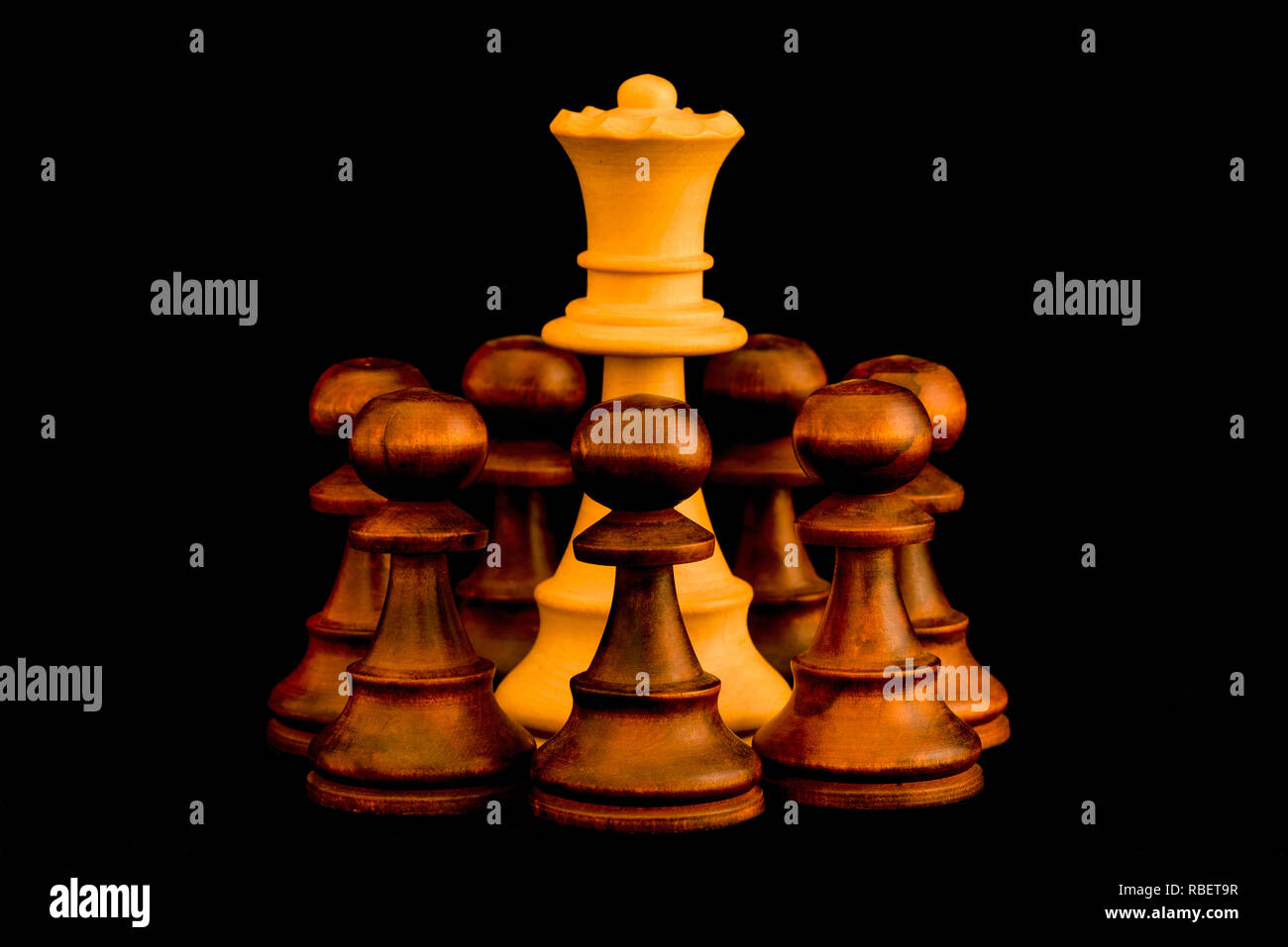 Under siege. White Queen beset by black enemy pawns with sense of no escape, standard chess wooden piece on black background Stock Photo