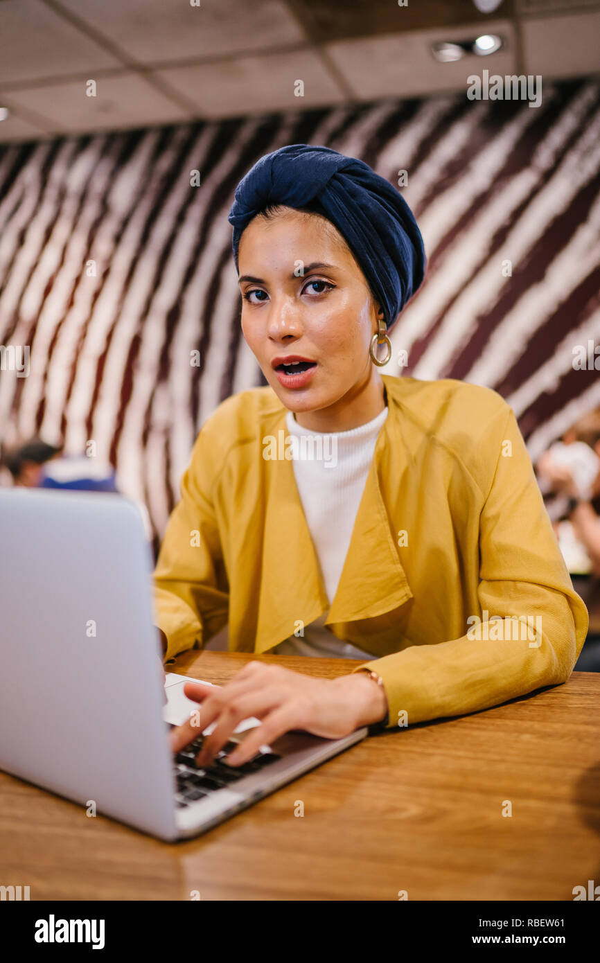 A young Malay Asian woman is typing and working or studying on her ...