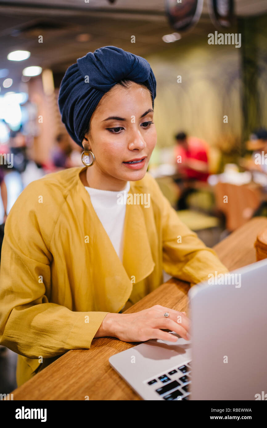 A young Malay Asian woman is typing and working or studying on her ...