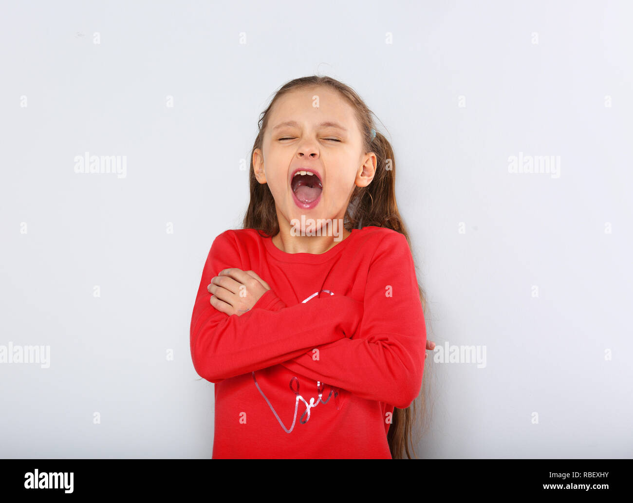 Kid girl strong screaming with open mouth and folded arms on blue background with empty copy space Stock Photo