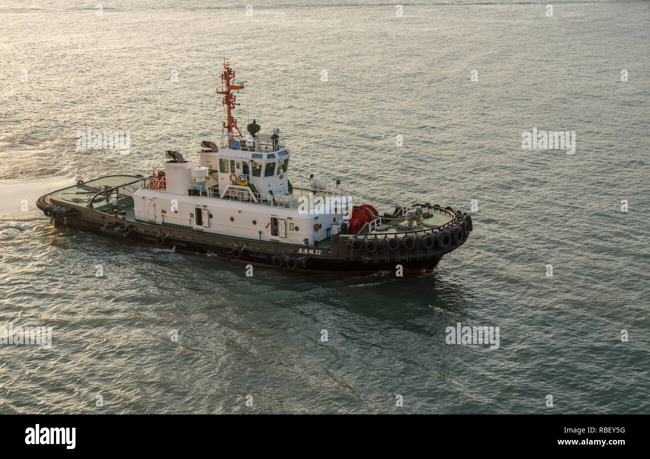 Tugboat escorting ship into Xiamen in China Stock Photo