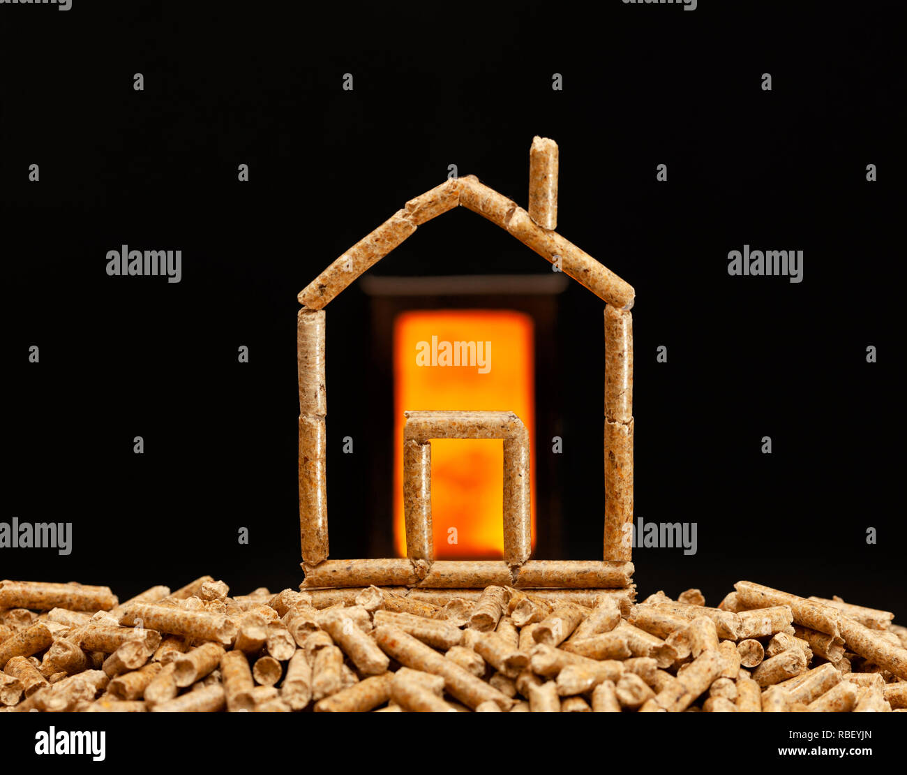 Miniature house made with wood pellets. Heating concept with combustion chamber in the background. Stock Photo