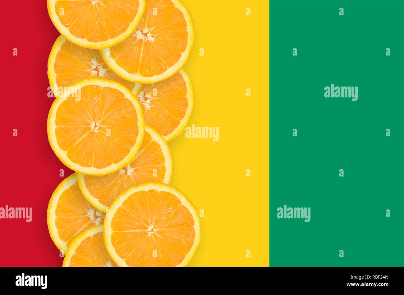 Guinea flag and vertical row of orange citrus fruit slices. Concept of growing as well as import and export of citrus fruits Stock Photo