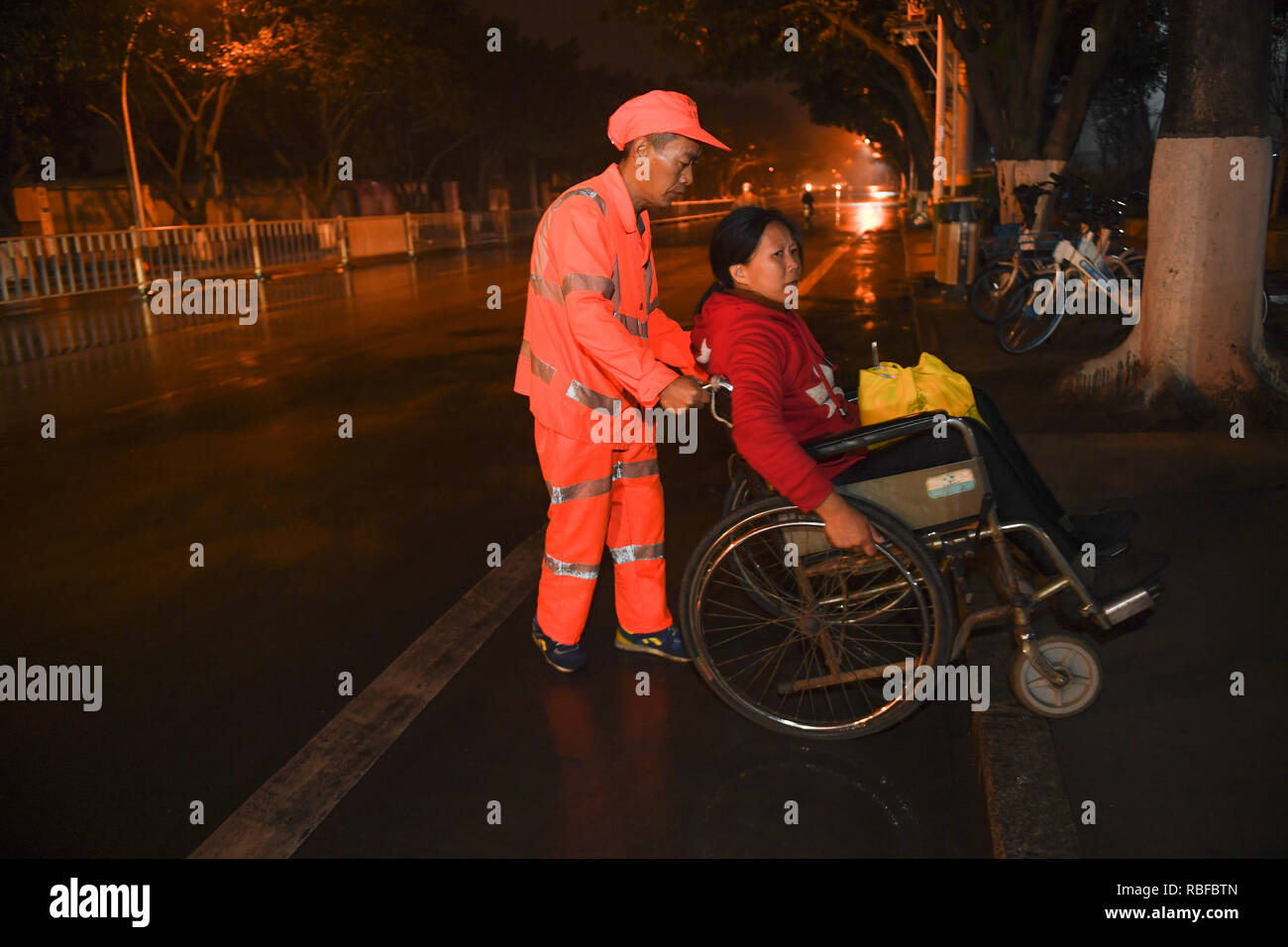 (190110) -- LONGYAN, Jan. 10, 2019 (Xinhua) -- Sanitation worker Dong Jidong pushes his wife Dong Jinxiang on a wheelchair before working in Xinluo District of Longyan City, southeast China's Fujian Province, Jan. 9, 2019. Due to femoral head necrosis disease, Dong Jinxiang has been living on a wheelchair for about a decade. To take care of his handicapped wife, Dong Jidong, who himself has been afflicted with ankylosing spondylitis, gave up his work in a cement plant and chose to clean the streets near their home two years ago just in order to take better care of his wife. Everyday, Dong Jido Stock Photo