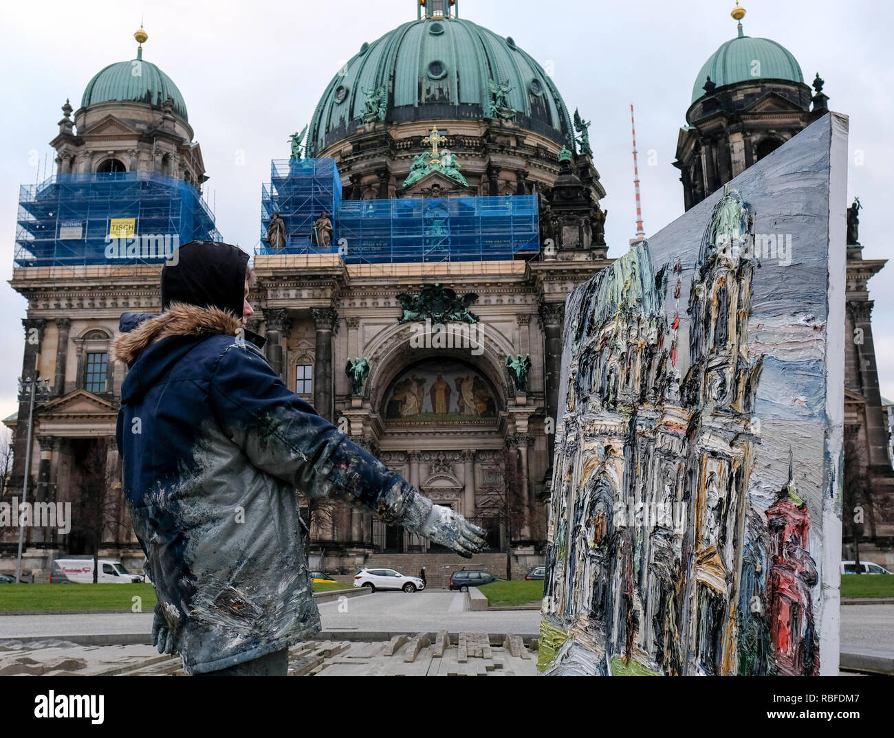 10 January 2019, Berlin: The painter Christopher Lehmpfuhl paints a picture with the Berlin Cathedral in the Lustgarten. The artist is known for painting large-format, color-intensive pictures in public or outdoors. He uses his fingers to apply the paint. Photo: Jens Kalaene/dpa-Zentralbild/ZB Stock Photo