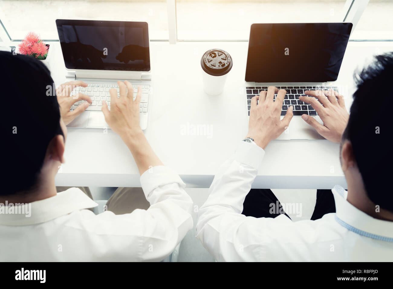Two friends business man sitting in cafe and drink coffee. top view of two colleagues business poeple working with laptop in coffee shop. Stock Photo