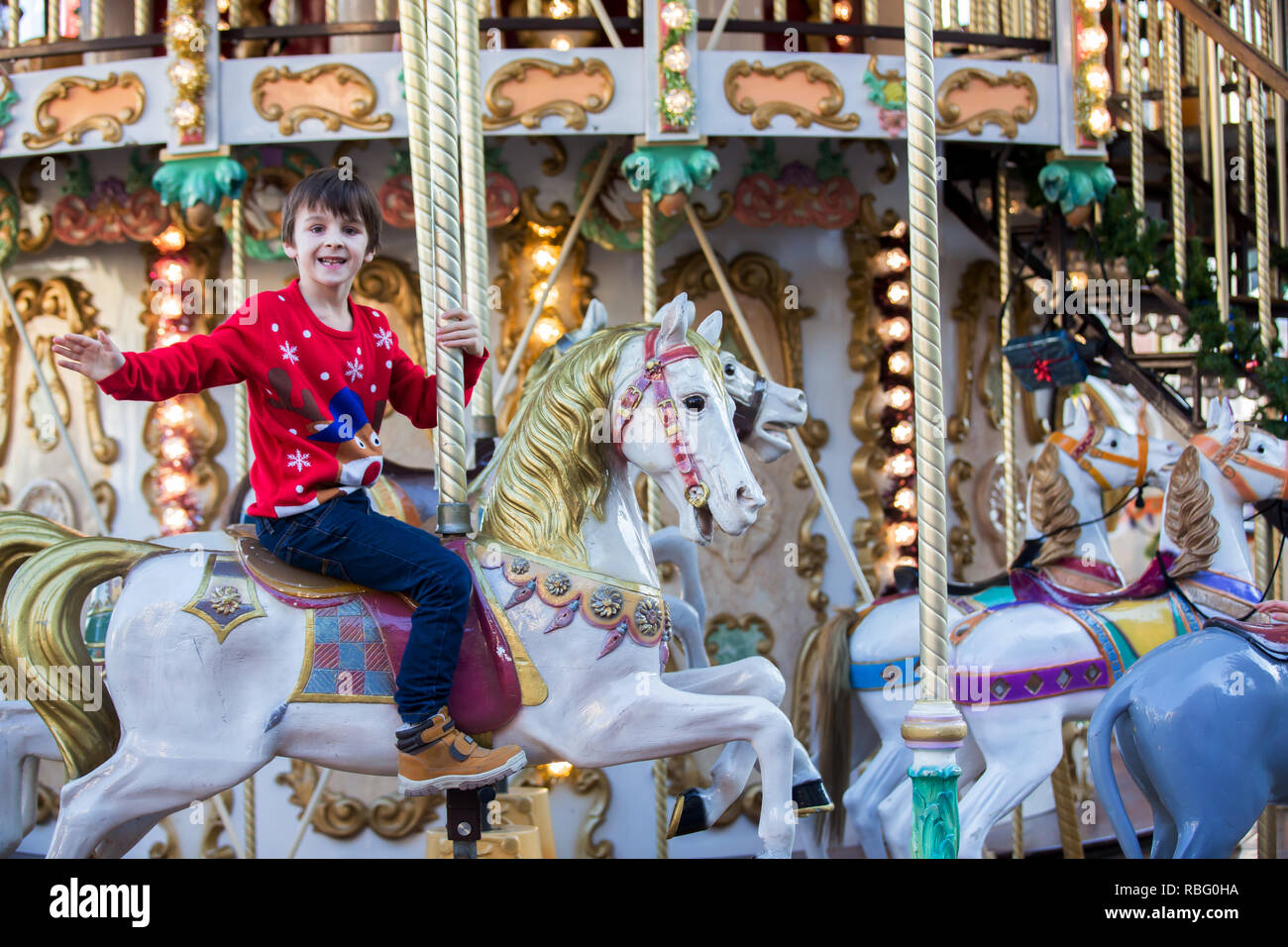 Sweet boys, brothers, riding in a Santa Claus sledge on a merry-go-round, carousel attraction in Europe, active children, wintertime Stock Photo