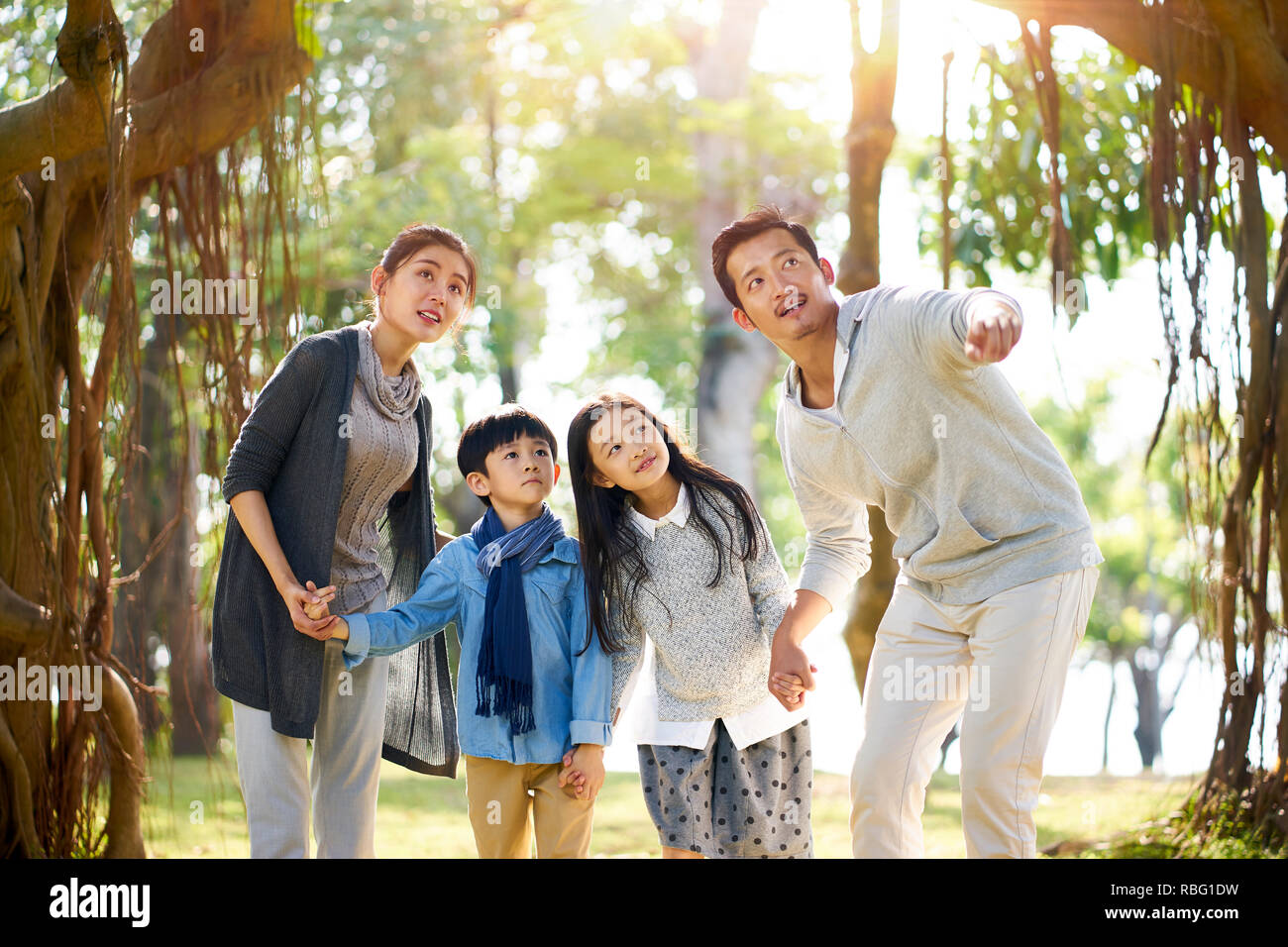 asian family with two children having fun exploring woods in a park. Stock Photo