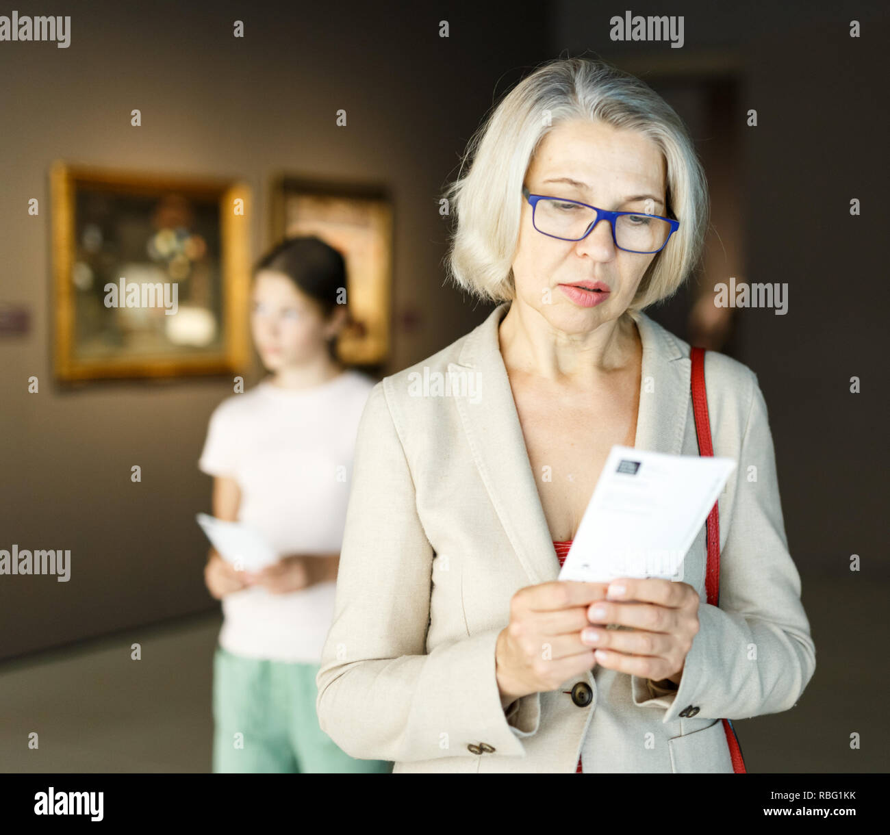 Attentive mature woman observing exhibition in art museum Stock Photo -  Alamy