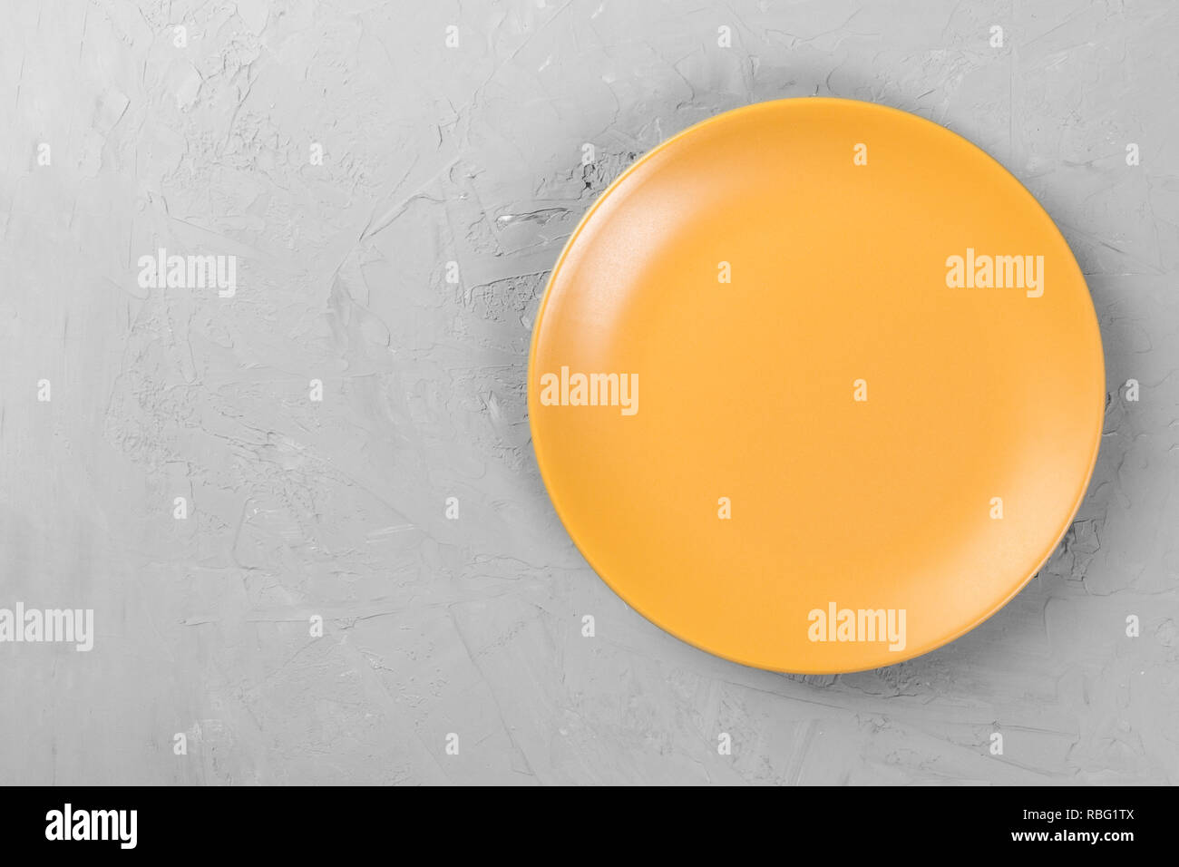 Top view of matte round empty orange plate on dark cement background ...