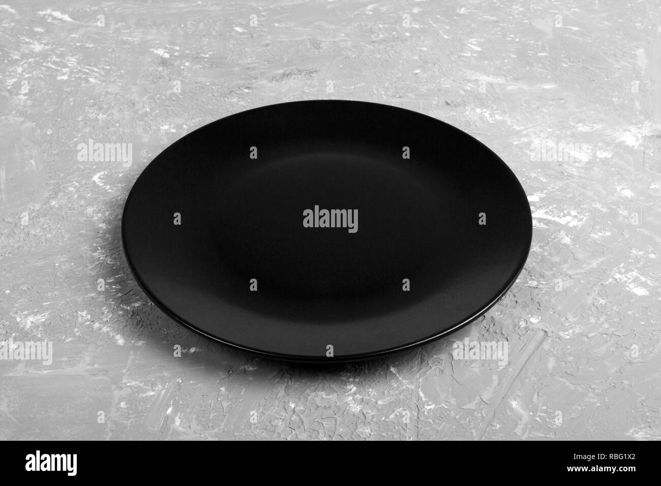 Top view of matte round empty black plate on dark cement background ...