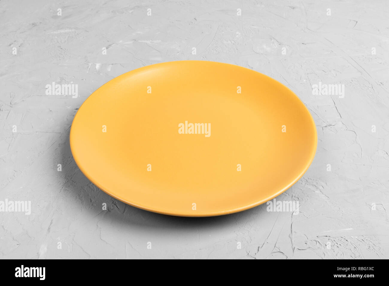 Top view of matte round empty yellow plate on grey cement background ...