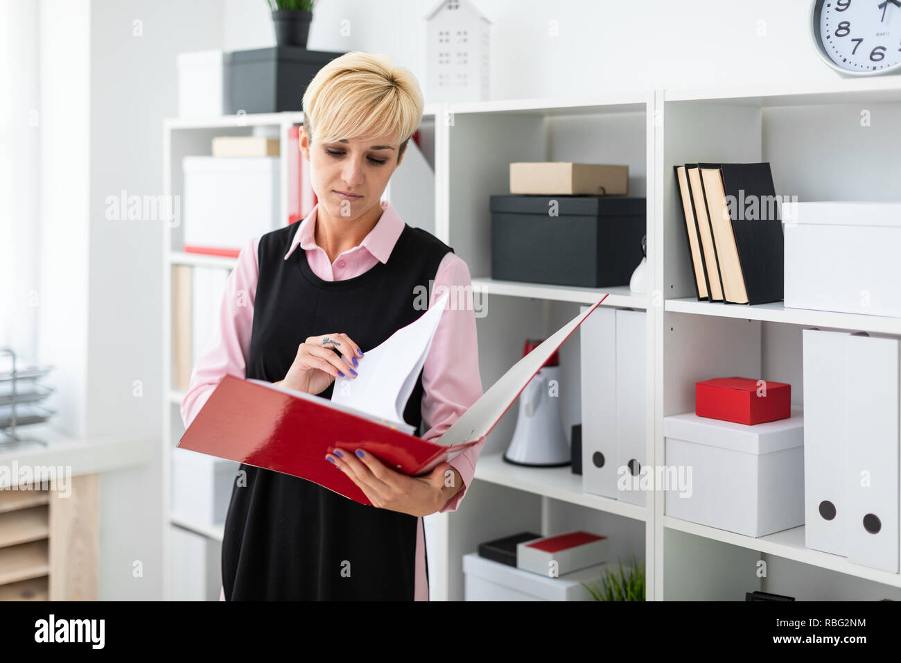 A young girl stands in the office with a red folder in her hands Stock ...