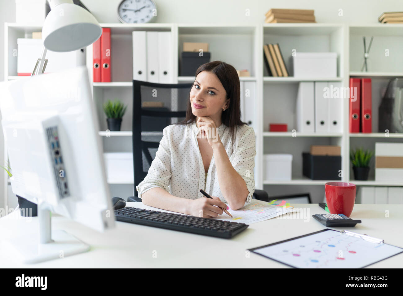 A young girl working in the office with documents and a computer ...
