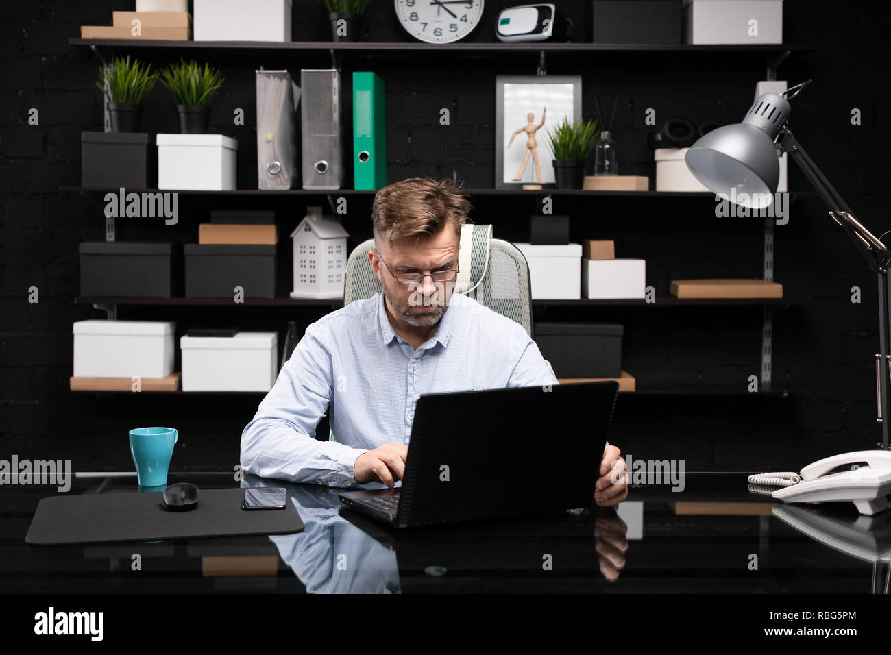 Serious businessman working on laptop and drinking coffee Stock Photo