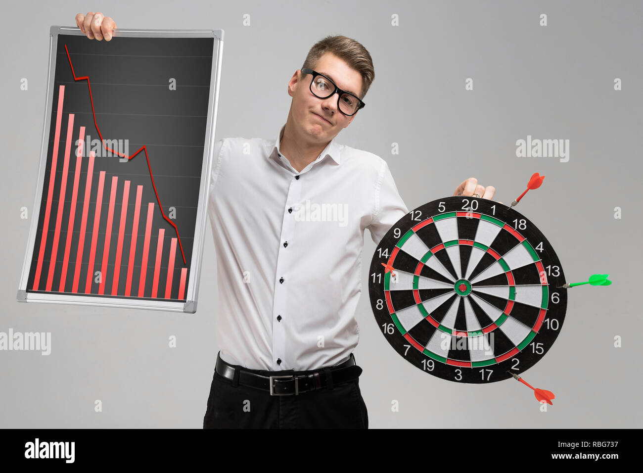 Young man in glasses holding a Board with falling statistics and Darts