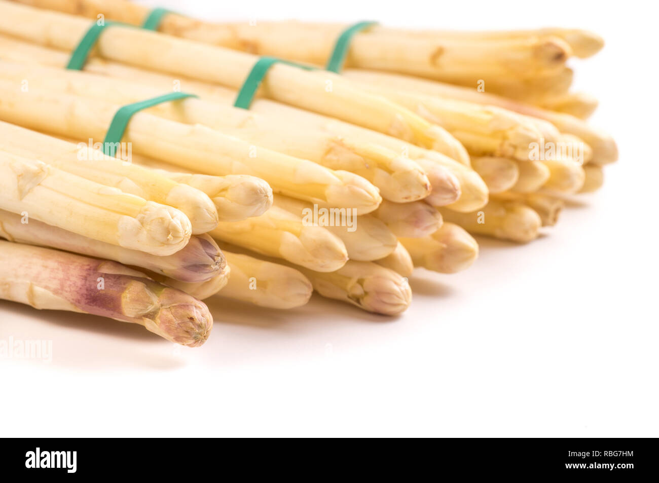 bundle of organic asparagus held together with green rubber bands isolated on white background Stock Photo
