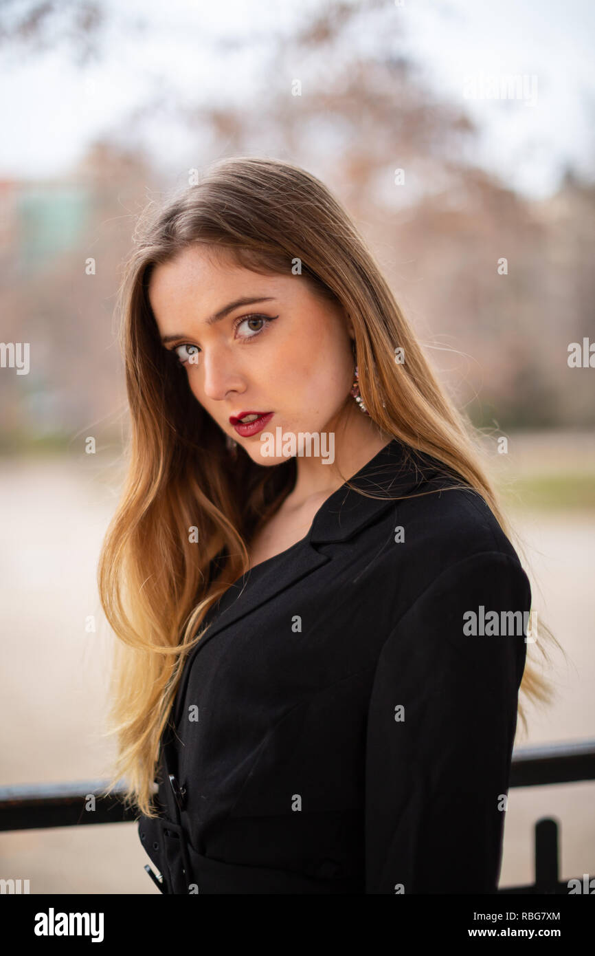 Pretty model woman posing in a park resting on a fence Stock Photo